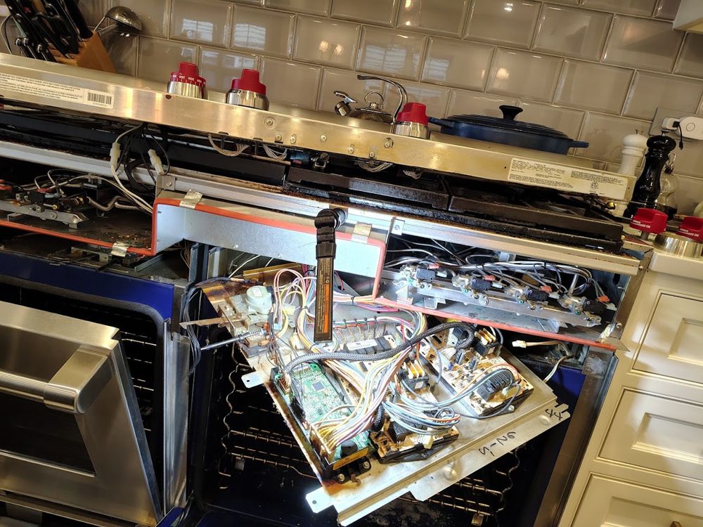 Range with the control panel pulled forward and the wiring exposed