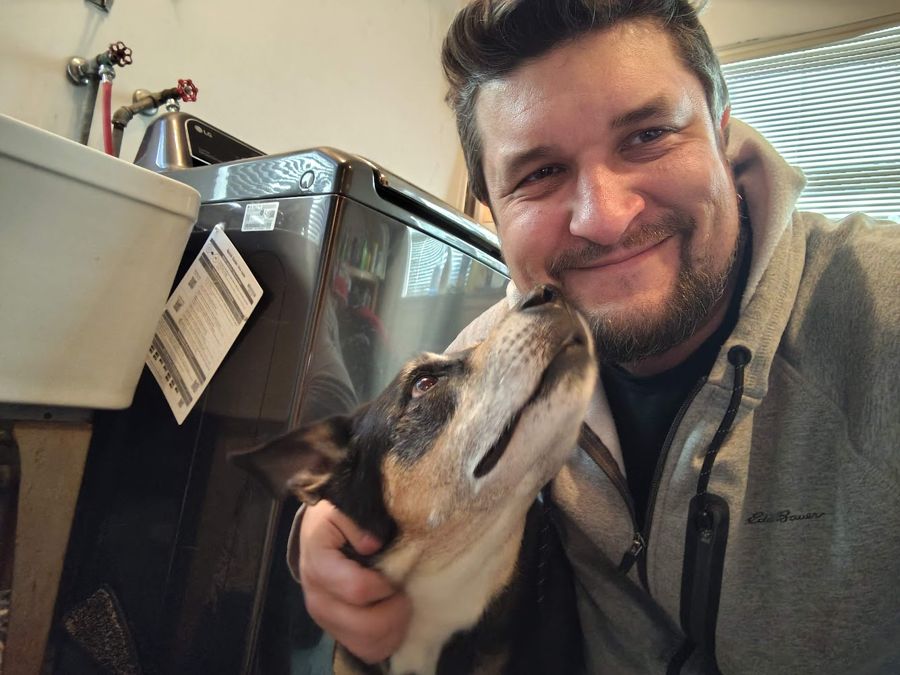 A customer's dog leaning in for a kiss while Max works on the washer