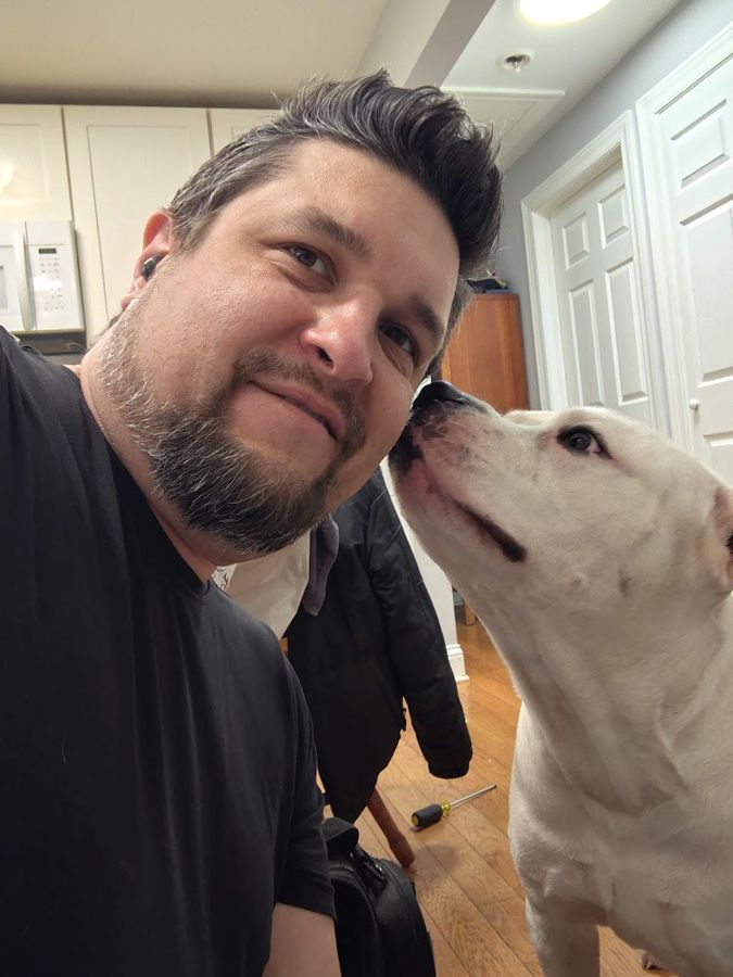 A customer's white dog giving Max a kiss